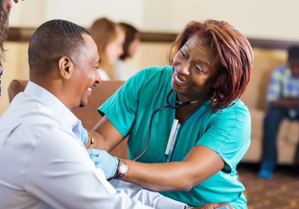 Nurse checking blood pressure for mature African American man