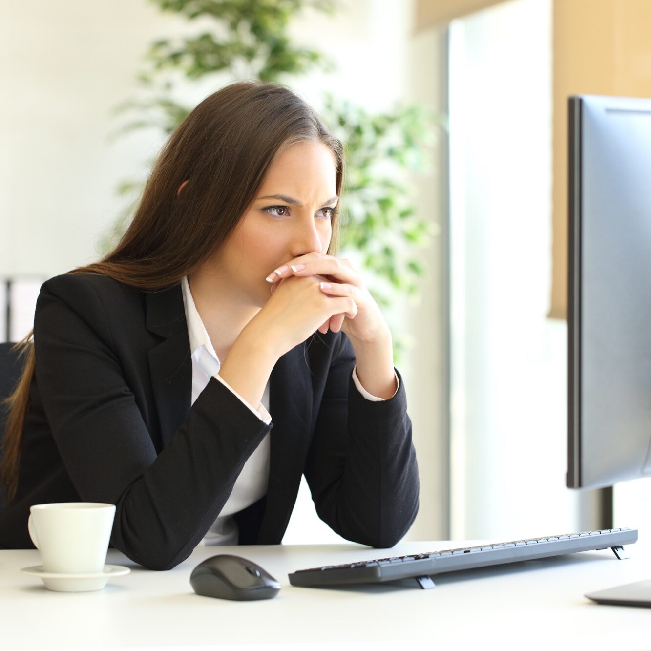 Concentrated businesswoman trying to solve a difficult assignment on line in a desktop computer at office